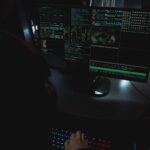 Dark room setup with code displayed on PC monitors highlighting cybersecurity themes.