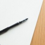 Black pen resting on an open grid notebook, perfect for writing or design.