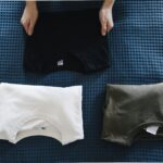 Top view of neatly folded colored T-shirts laid out on a blue bedspread, perfect for housekeeping themes.